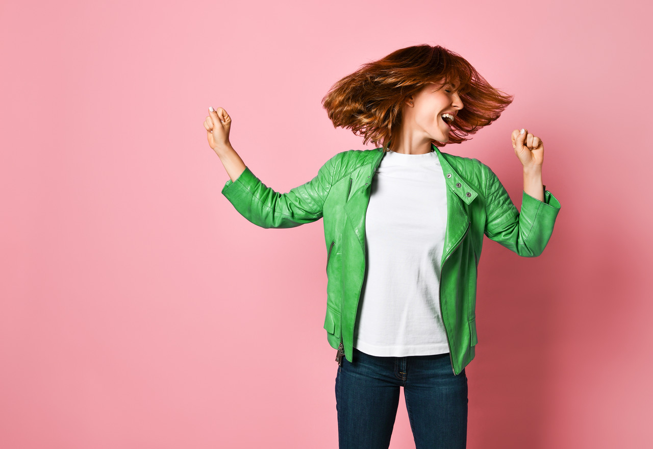 Young Woman Wearing Jeans And A Jacket Is Shaking Her Head With Her Hair. The Concept Of Joy, Happin